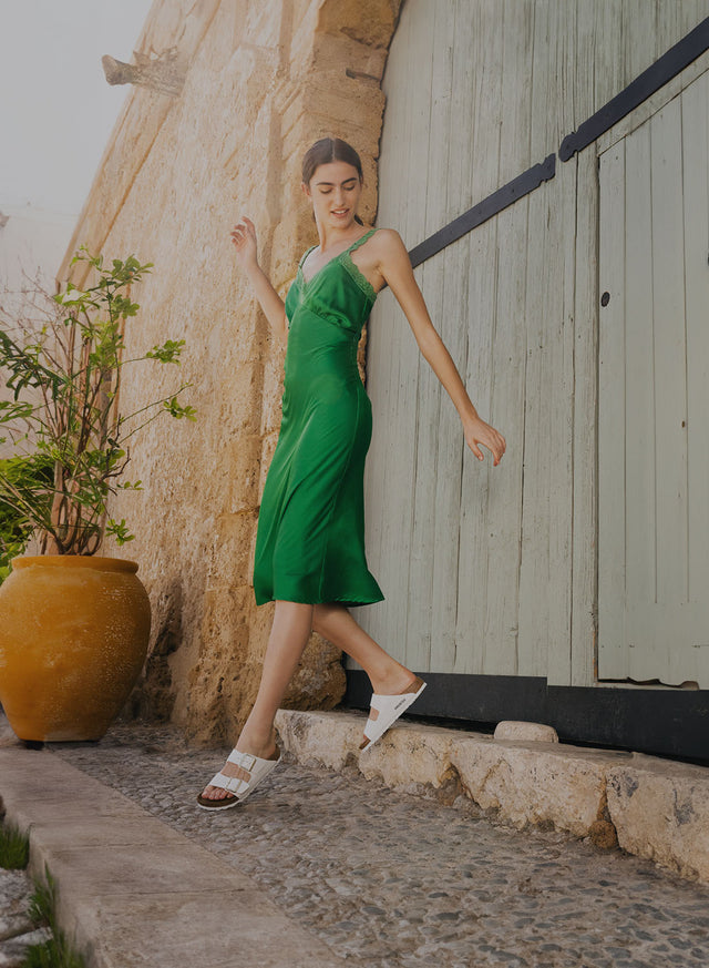 donna con vestito verde che cammina in città e indossa birkenstock arizona bianche